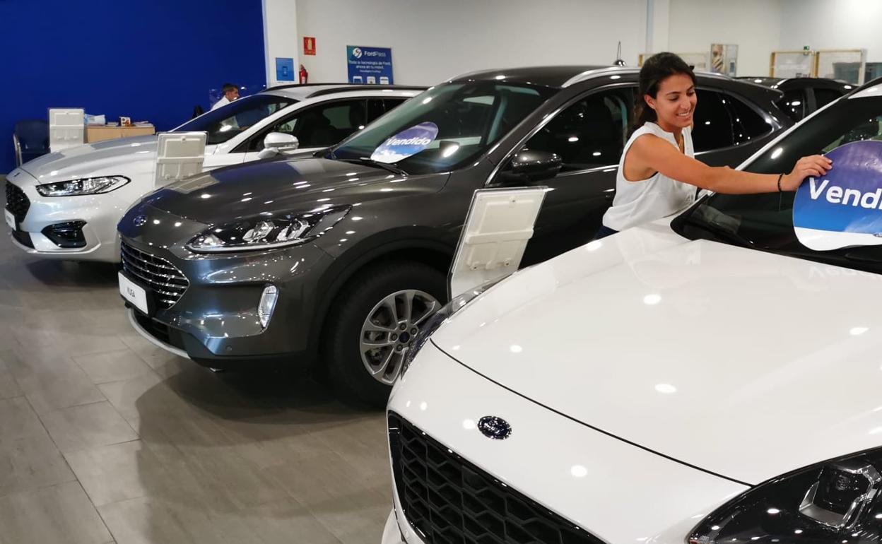 Una empleada coloca el cartel de vendido en un coche expuesto en un concesionario. 