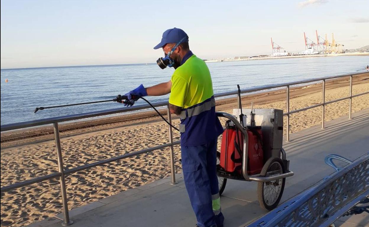 Un operario desinfecta la barandilla de acceso a la playa. 