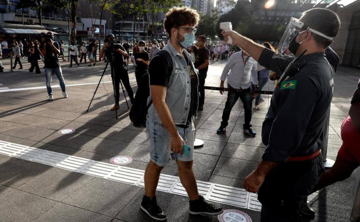 Un funcionario mide la temperatura de un cliente a la entrada de un comercio de Sao Paulo (Brasil) 