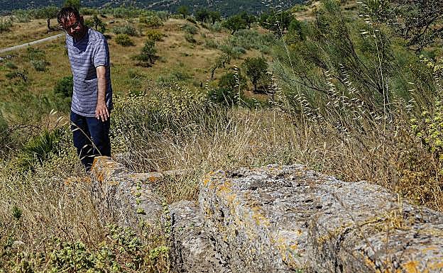 Imagen principal - Arriba, Francisco Marmolejo señala un muro del alcázar de Bobastro con un estilo constructivo precedente de Medina Azahara. Abajo, talla con el rostro del sublevado Ibn Hafsún y una cruz bajorrelieve en piedra en el yacimiento malagueño.