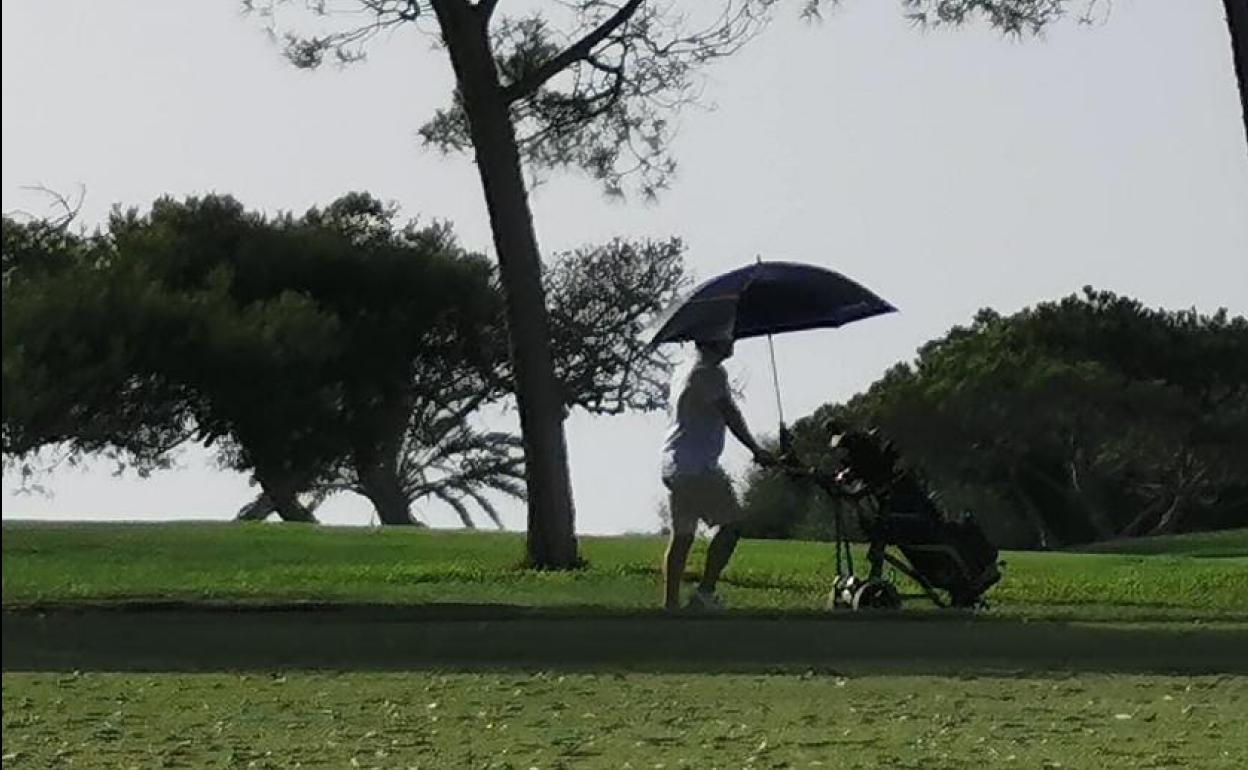 Un hombre se protege del sol esta mañana en un campo de golf.