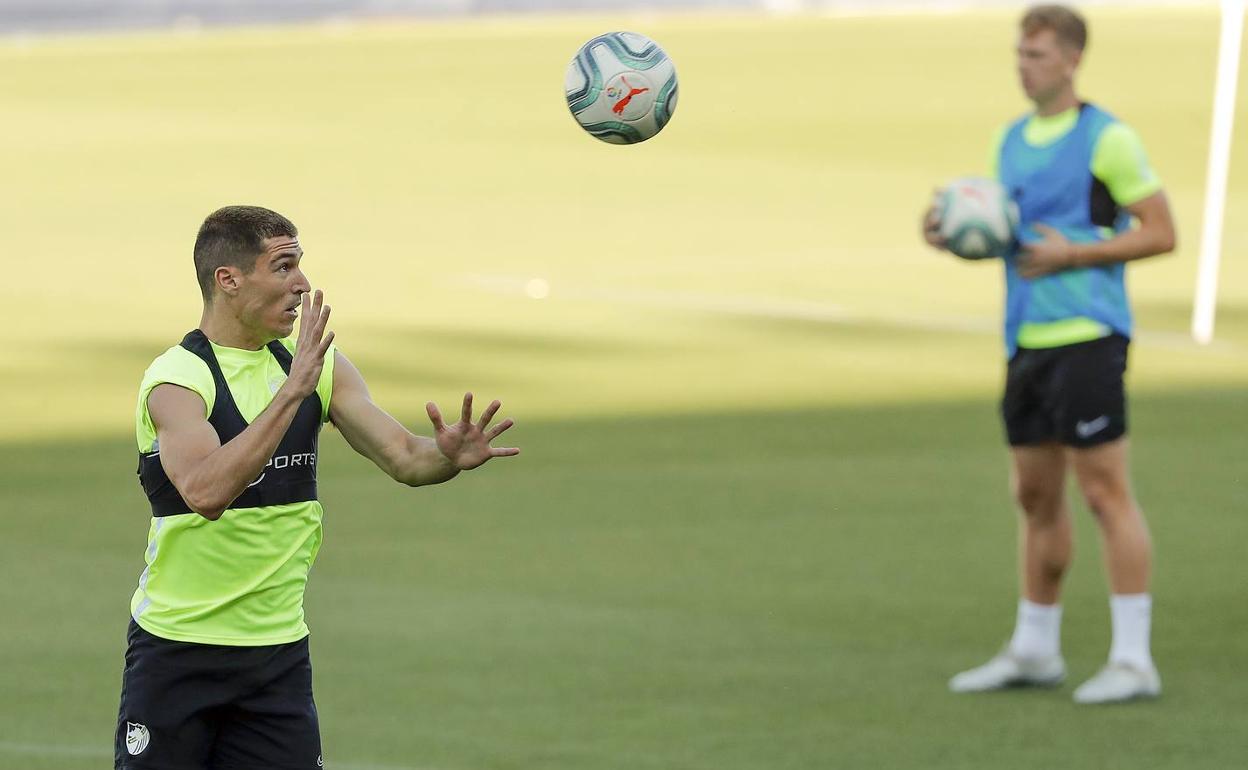 Diego González golpea la pelota de cabeza en un entrenamiento con Rolón en segundo plano. 