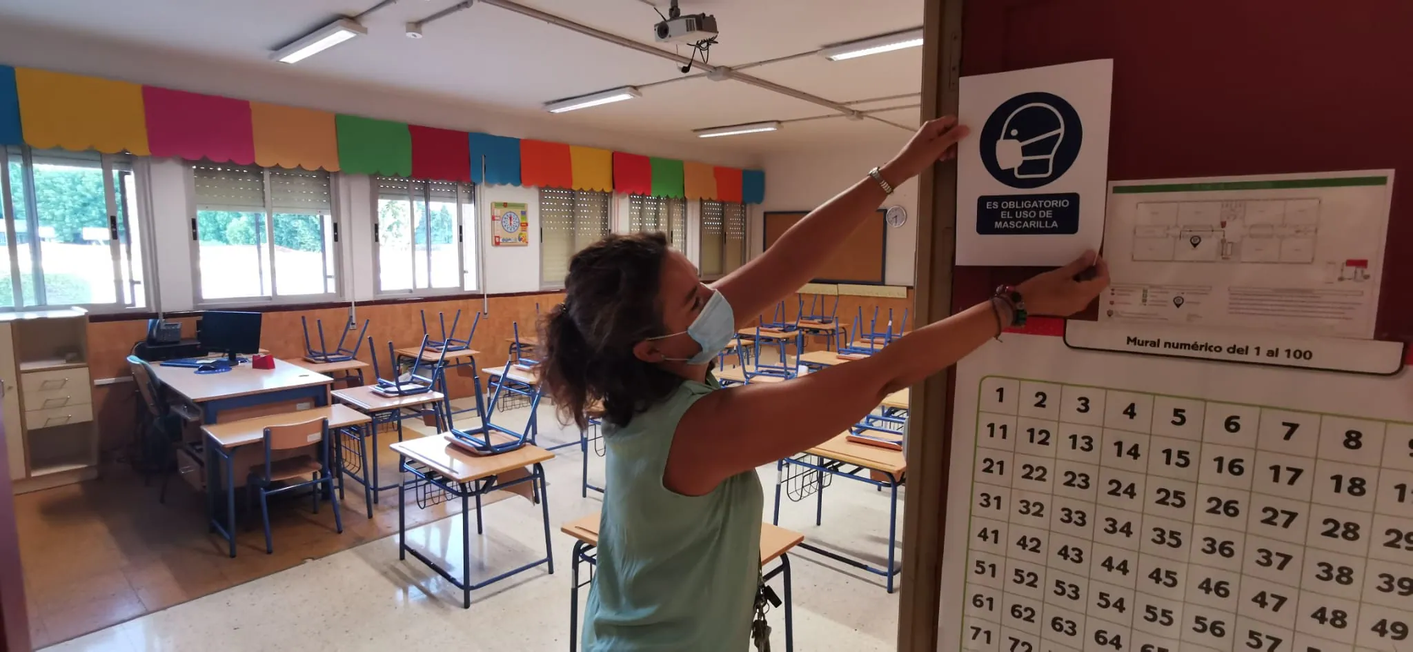 La directora del colegio Arturo Reyes de la capital coloca un cartel advirtiendo de la obligatoriedad de las mascarillas en el centro escolar.
