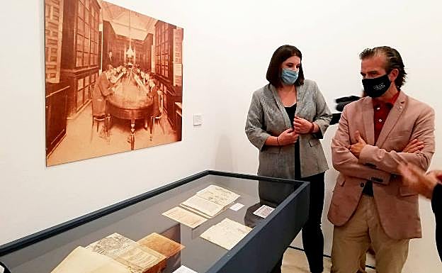 Imagen principal - El diputado de Cultura, Víctor González, visita la exposición con la comisaria. Abajo, uno de los libros expuestos y el retrato de Suceso Luengo.