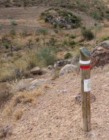 Imagen secundaria 2 - Arriba, este itinerario homologado tiene una longitud de 28 kilómetros.. Abajo, a la izquierda, el sendero está señalizado con las franjas roja y blanca, y, a la derecha, hito de la ruta.