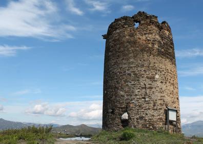 Imagen secundaria 1 - Arriba, conocida como La Atalaya, tiene una altura de 9,5 metros. Abajo, la torre está en el punto más elevado de esta ruta, y, a la derecha, el pantano de La Viñuela y, al fondo, el pueblo de Periana