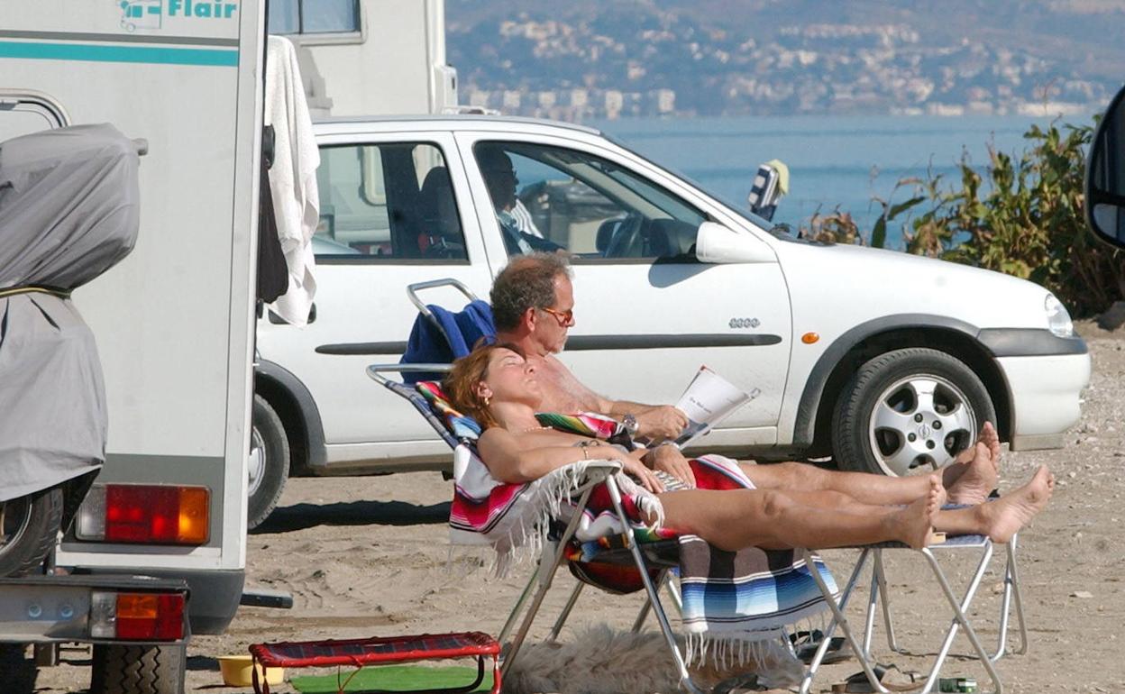 Un turista disfruta del sol junto al mar en un recorrido en autocaravana por la Costa.