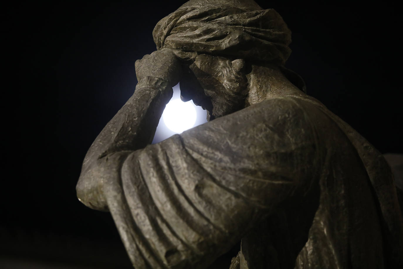La luna entre el brazo del hombre del monumento de los musulmanes que dejaron Antequera en 1410 y se trasladaron a Granada