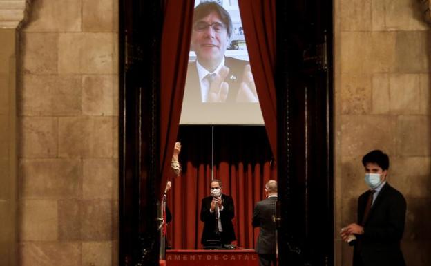 El expresidente de la Generalitat, Quim Torra, recibe el aplauso del expresidente Carles Puigdemont (en la pantalla) y los diputados de JxCat a su llegada a la reunión que mantuvieron en el Parlament el 30 de septiembre. 