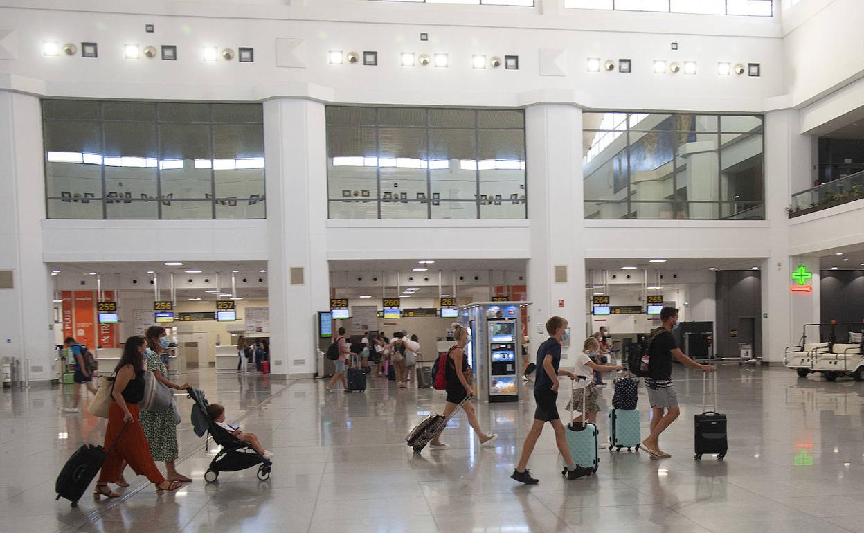 Turistas se dirigen a los controles de seguridad del aeropuerto para emprender sus viajes. 