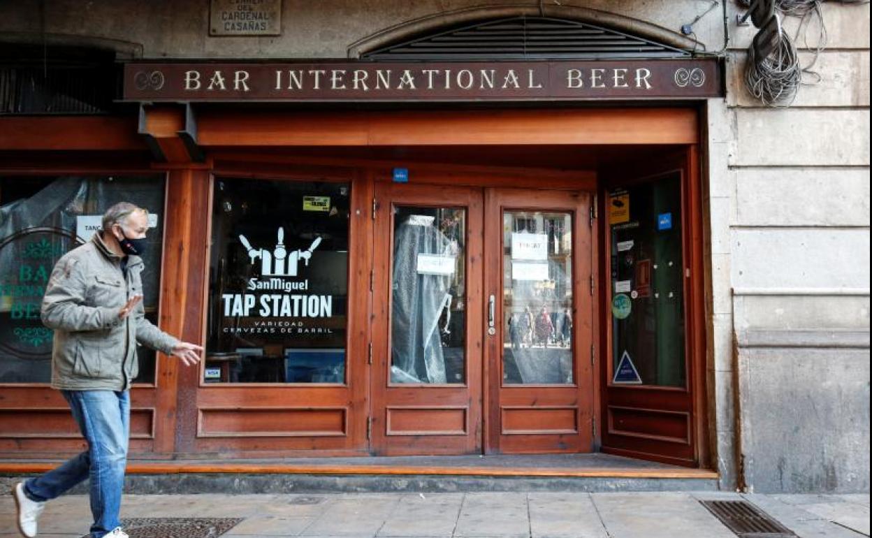 Un hombre pasa junto a un bar cerrado en Barcelona. 