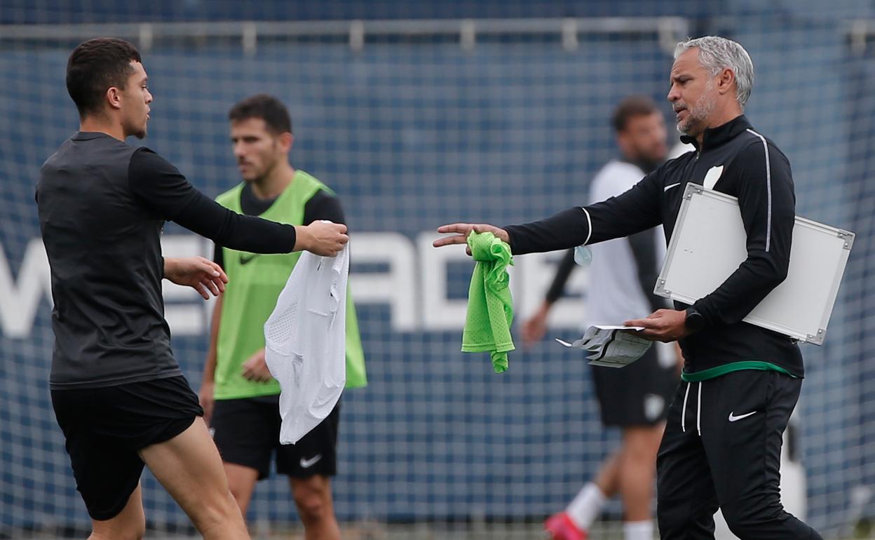 El entrenador del Málaga, Pellicer, entrega un peto al extremo Rahmani en un entrenamiento.