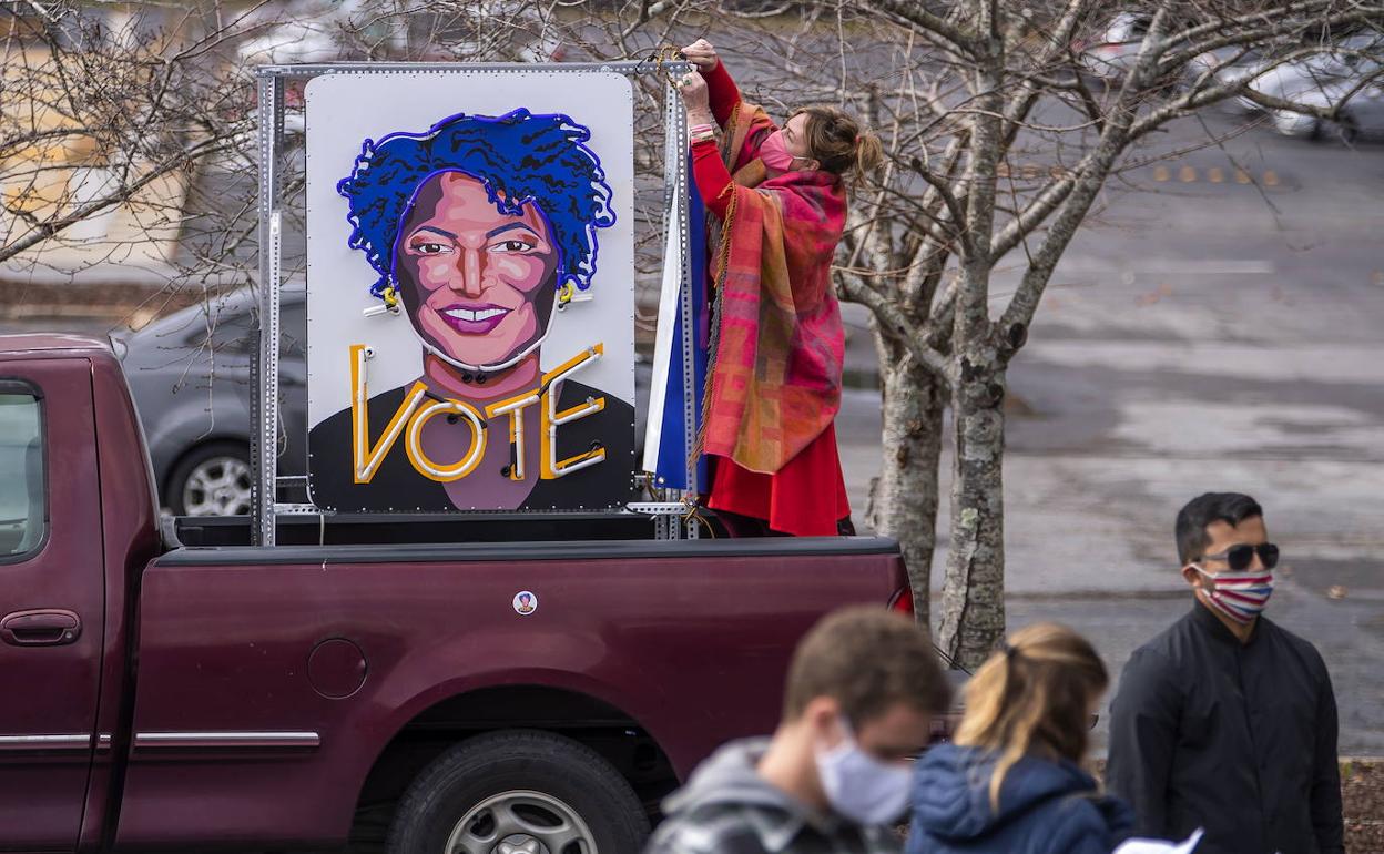 Una mujer latina de Lilburn porta en su vehículo un cartel de Stacey Abrams.