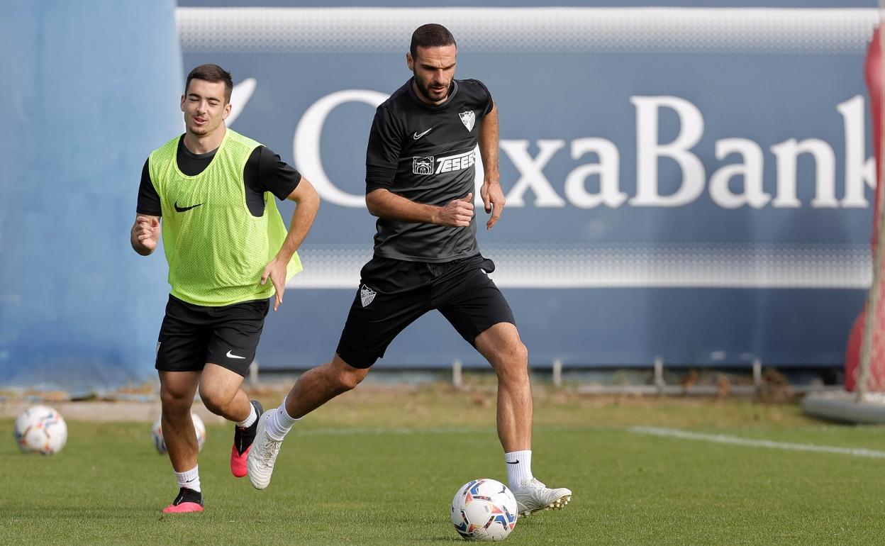 El jugador del Málaga, Lombán, conduce un balón durante un entrenamiento del Málaga. Al fondo, el centrocampista Ramón. 