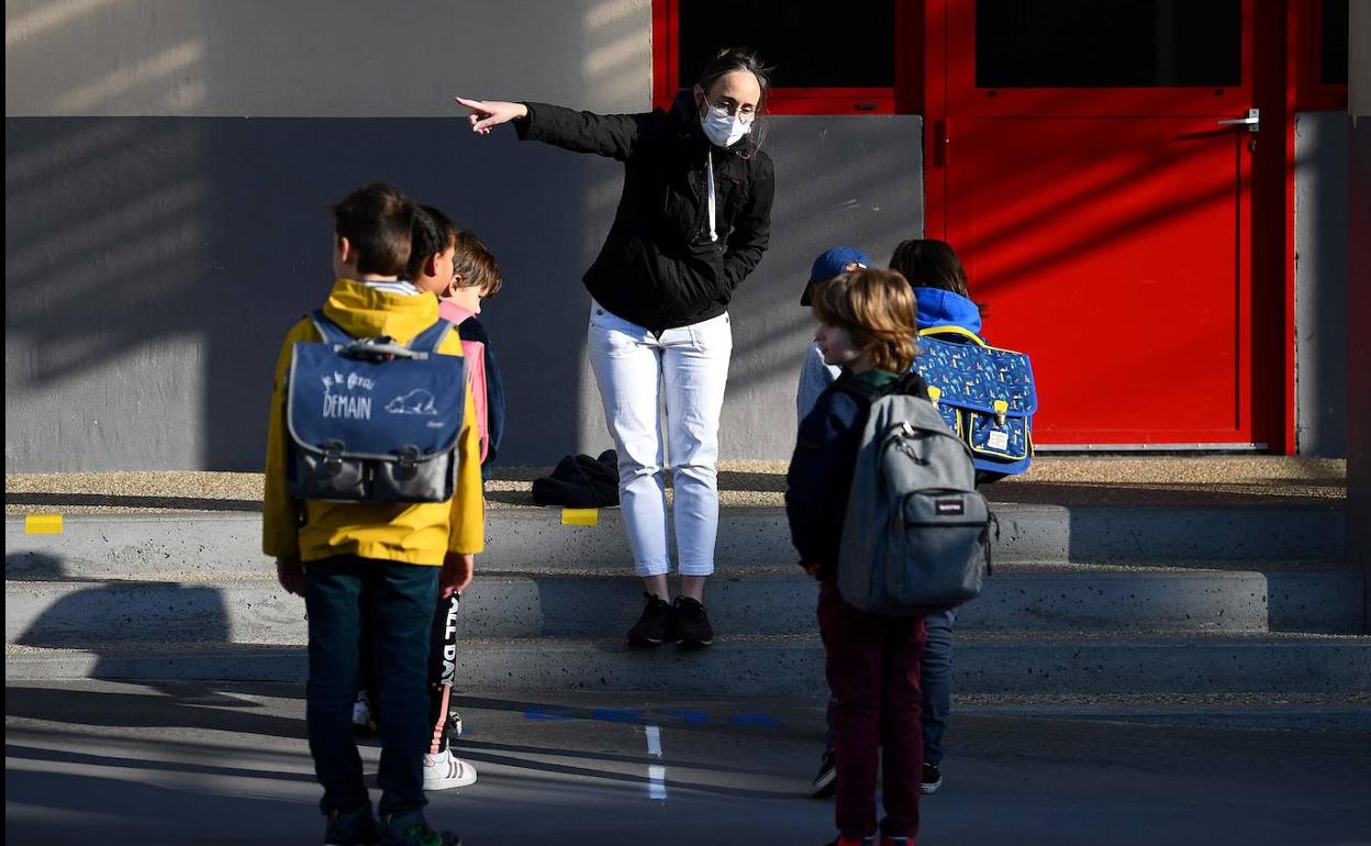 Una profesora organiza la entrada al colegio a un grupo de alumnos franceses según las normas sanitarias.