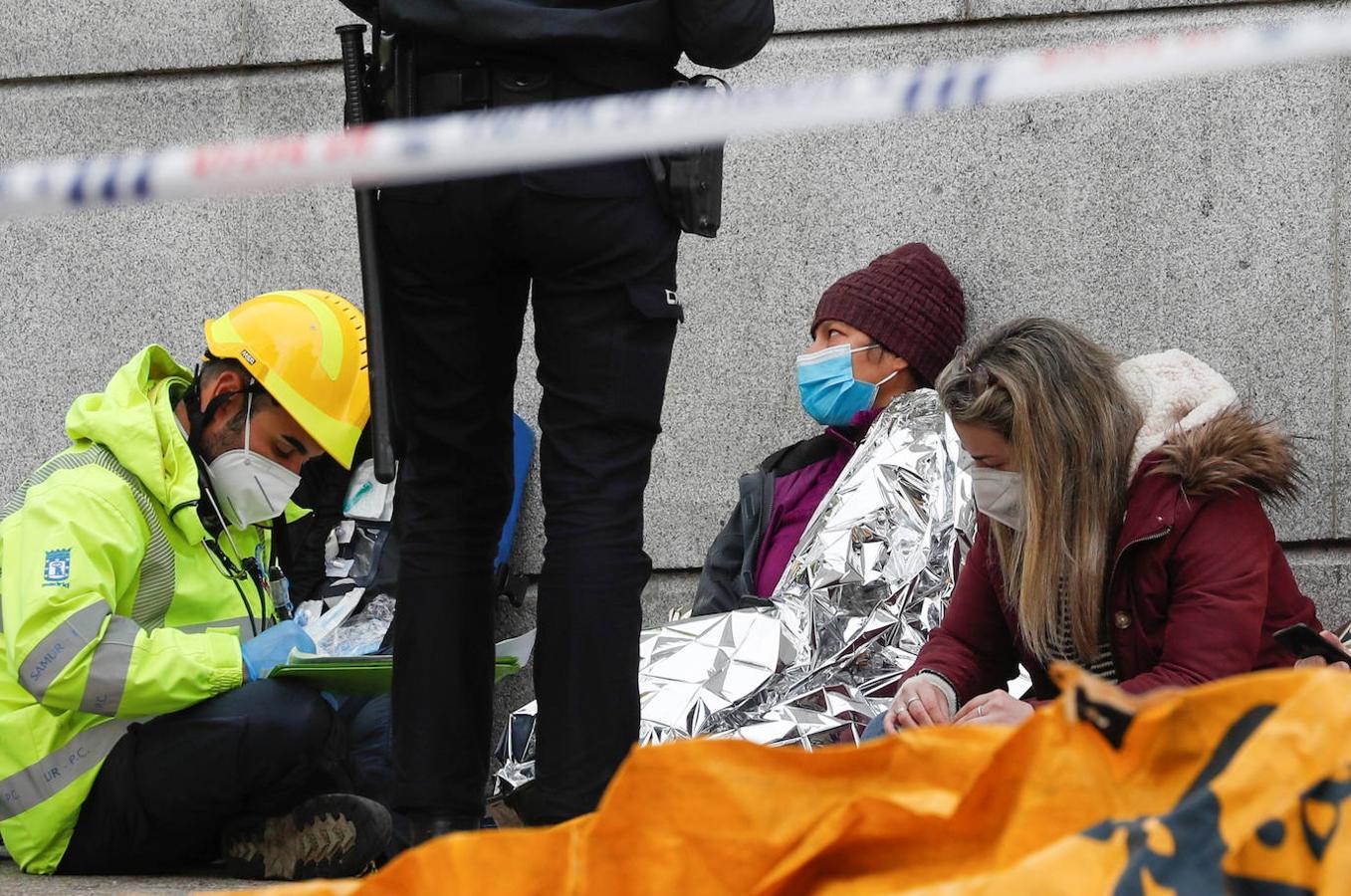 Un oficial de policía y personal médico asisten a personas tras la explosión en un edificio del centro de Madrid.
