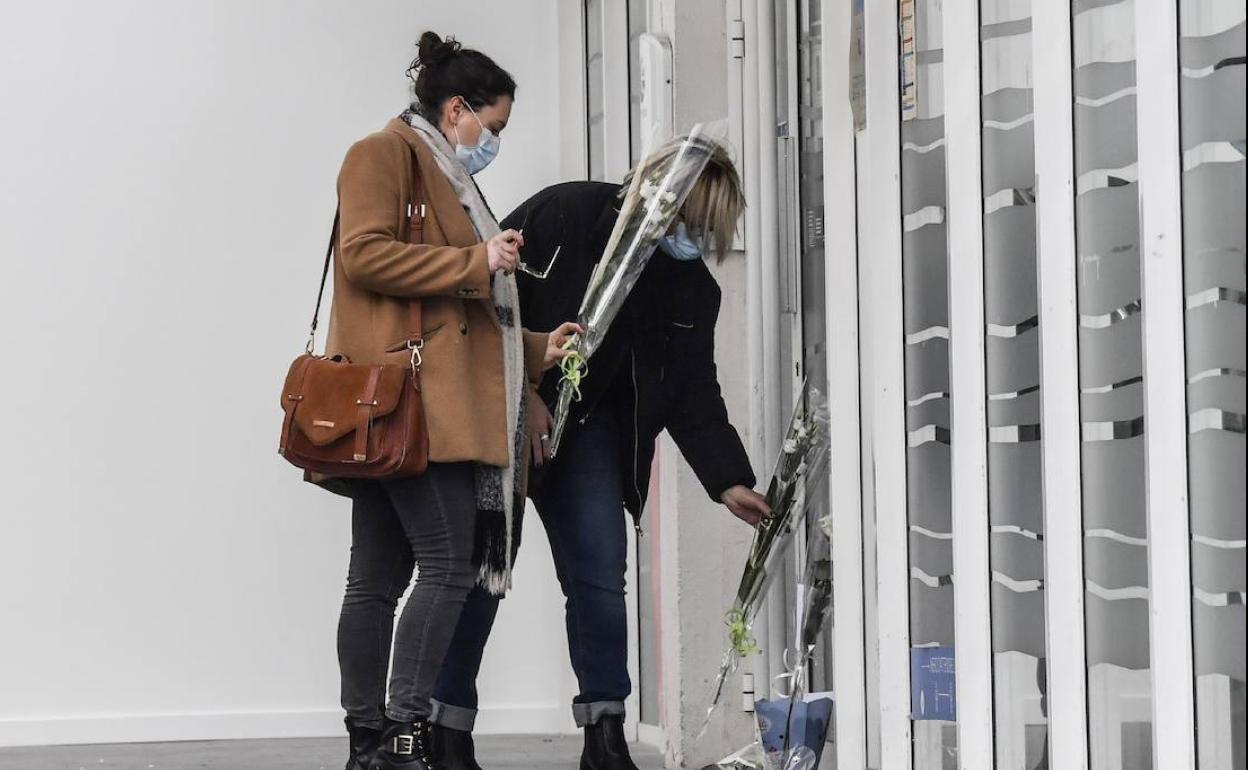 Dos mujeres depositan flores en la oficina de empleo donde tuvieron lugar los crímenes.