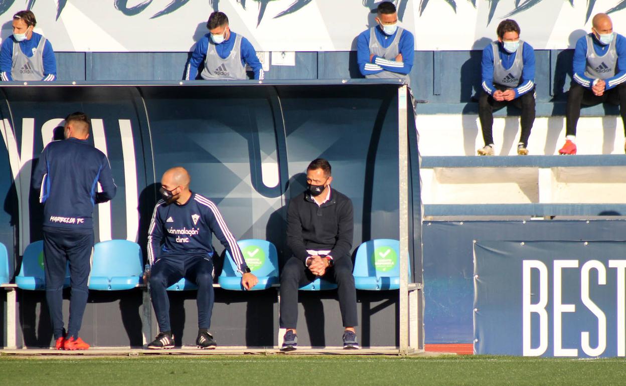 Aira, a la derecha, medita sentado en el banquillo del Marbella.
