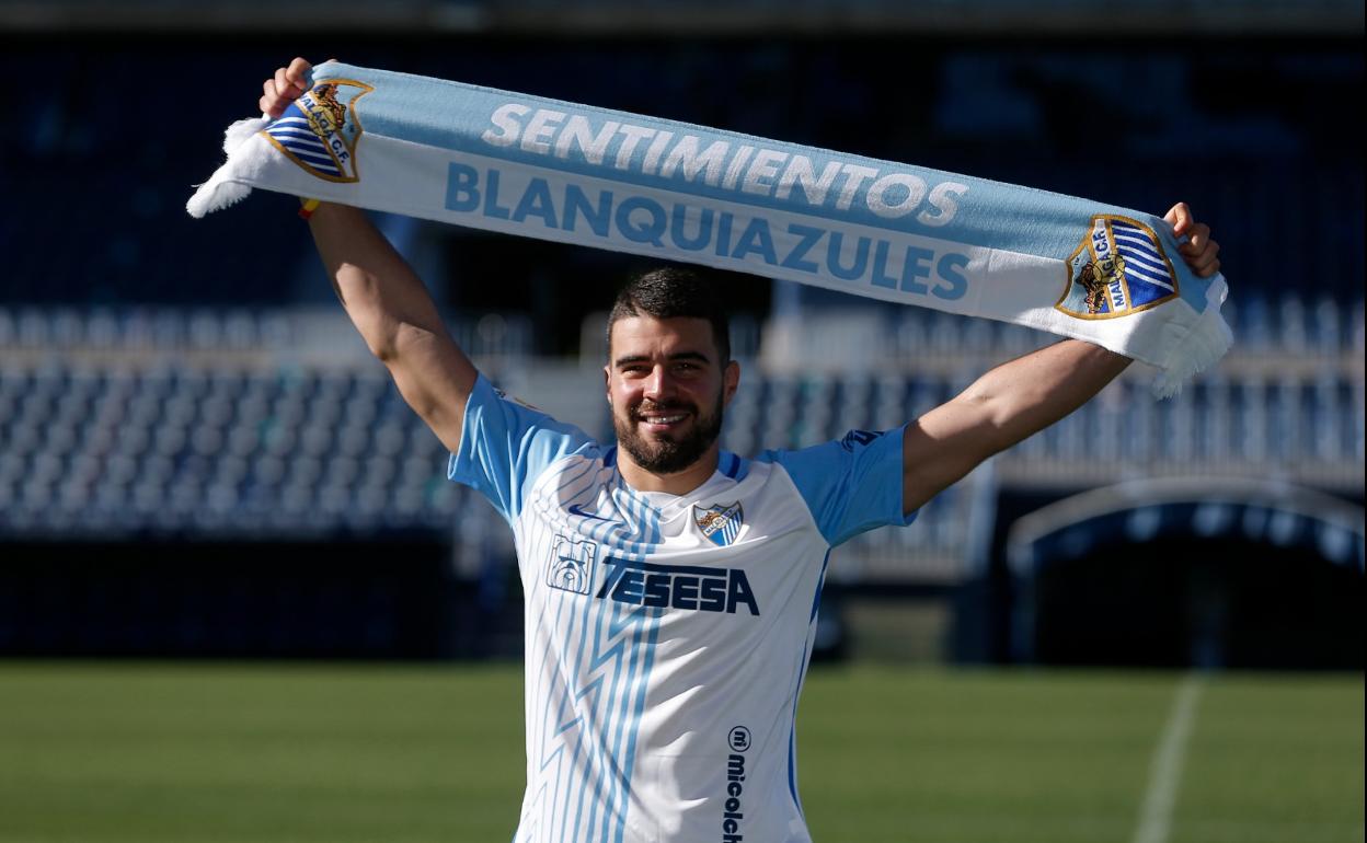 El futbolista Alexander González posa con una bufanda del Málaga sobre el césped de La Rosaleda en la presentación oficial de su fichaje por el club blanquiazul.