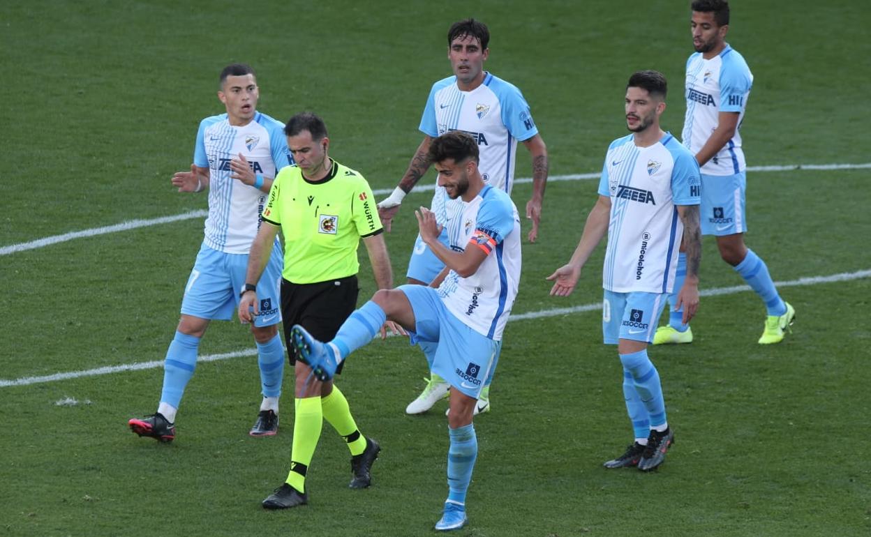 Los jugadores malaguistas se quejan a Ocón Arraiz por la acción del gol del Tenerife, e incluso Luis Muñoz hace un gesto imitando la acción antideportiva de Folch. 
