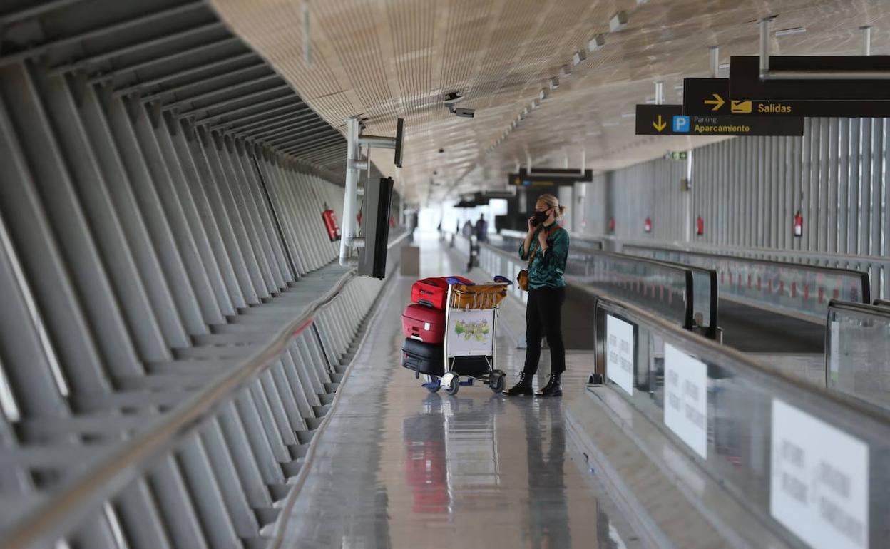 Una viajera mira el panel en un pasillo del aeropuerto que evidencia la baja actividad. 