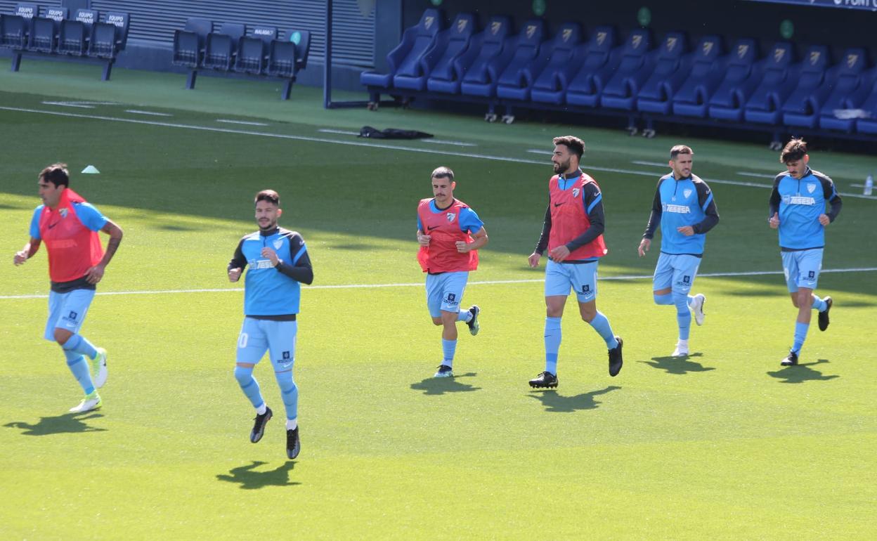 Jugadores del Málaga (Alberto Escassi, Caye Quintana, Matos, Juande, Jairo Sampeiro, Jozabed) saltan al terreno de juego del estadio de La Rosaleda para el calentamiento en un partido de esta temporada.