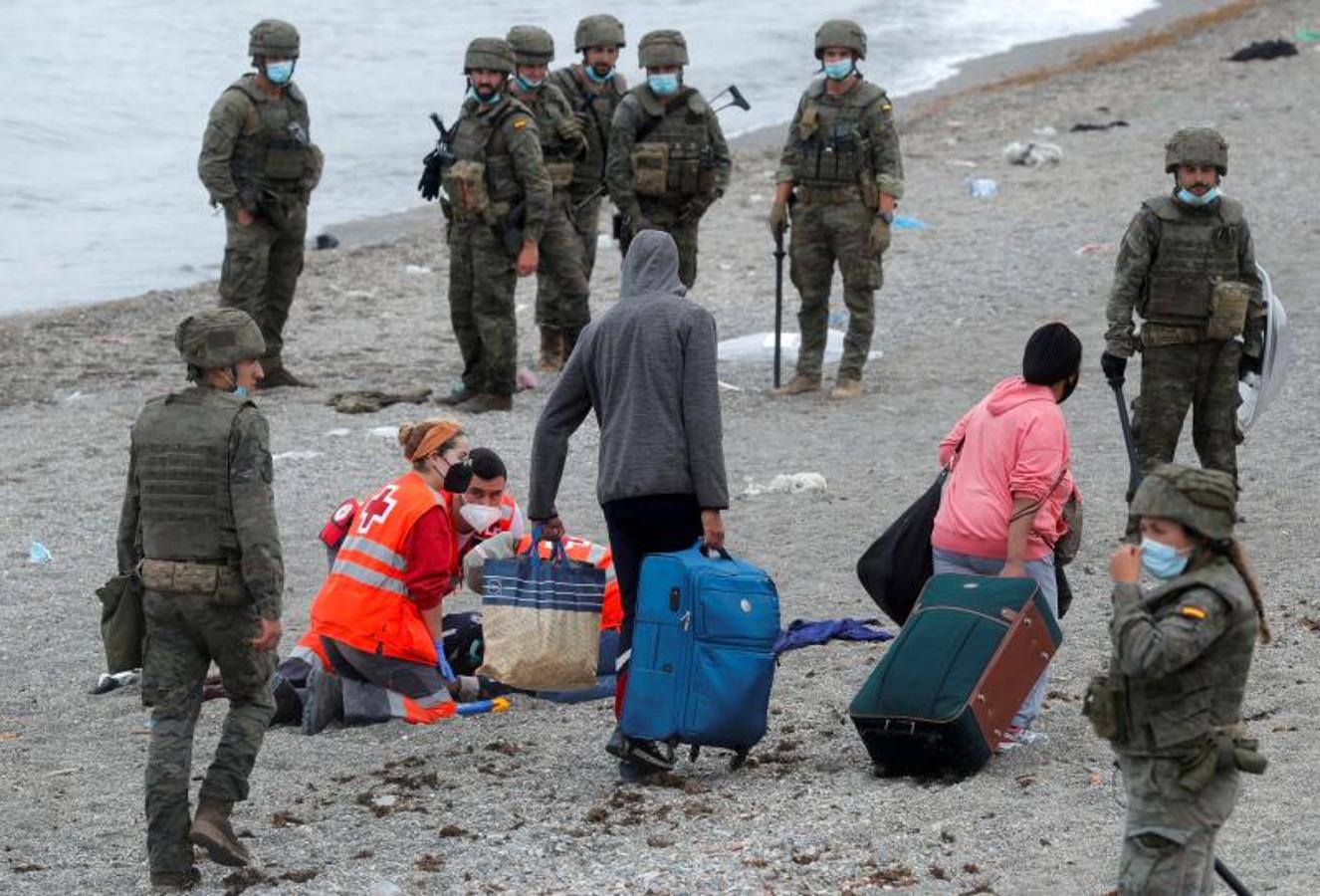 Miembros de la Cruz Roja atienden a una persona en la arena de la playa. 