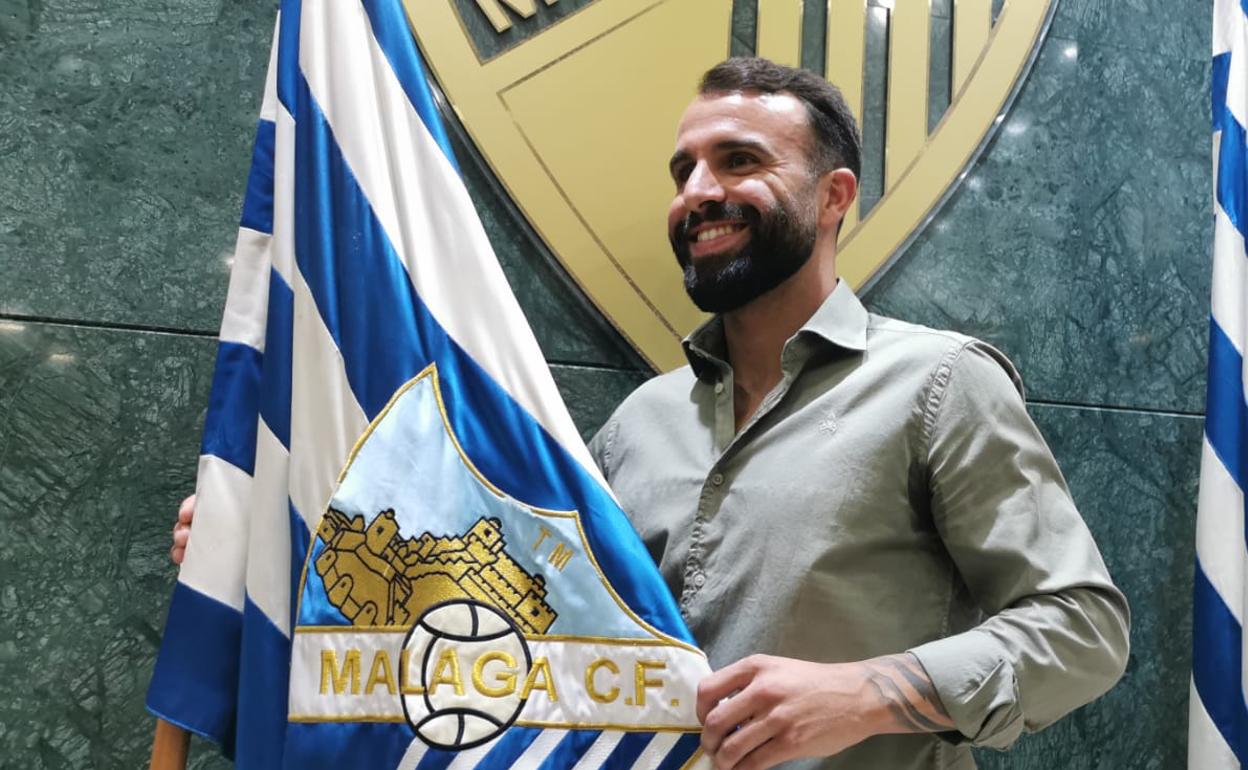 -Javi Jiménez posa sonriente con la bandera del Málaga tras ser presentado. 