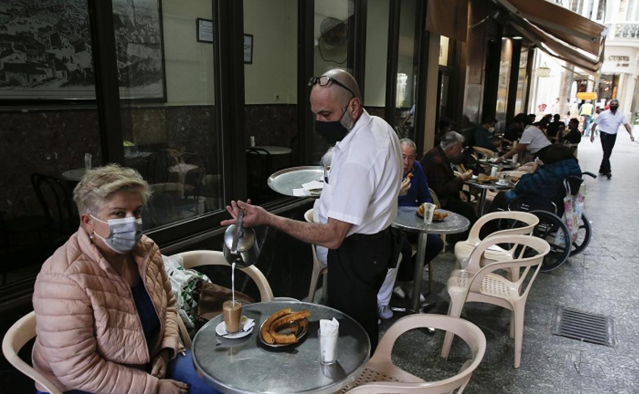 Un camarero sirve a una cliente en una terraza del Centro. 