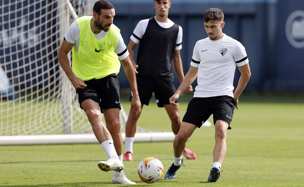 Los jugadores del Málaga David Lombán y el canterano Benítez durante el entrenamiento de este lunes en el Anexo de La Rosaleda.