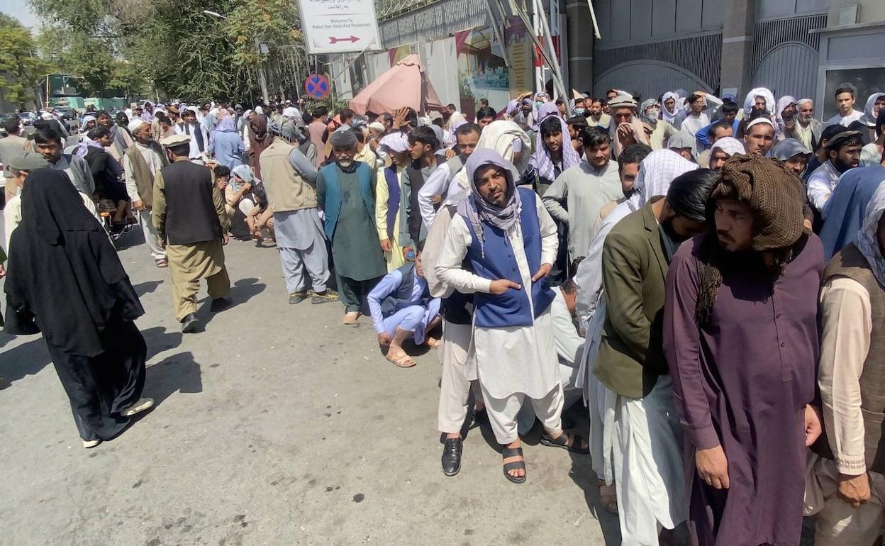 Decenas de personas guardan su turno para sacar dinero de una sucursal bancaria en Kabul.