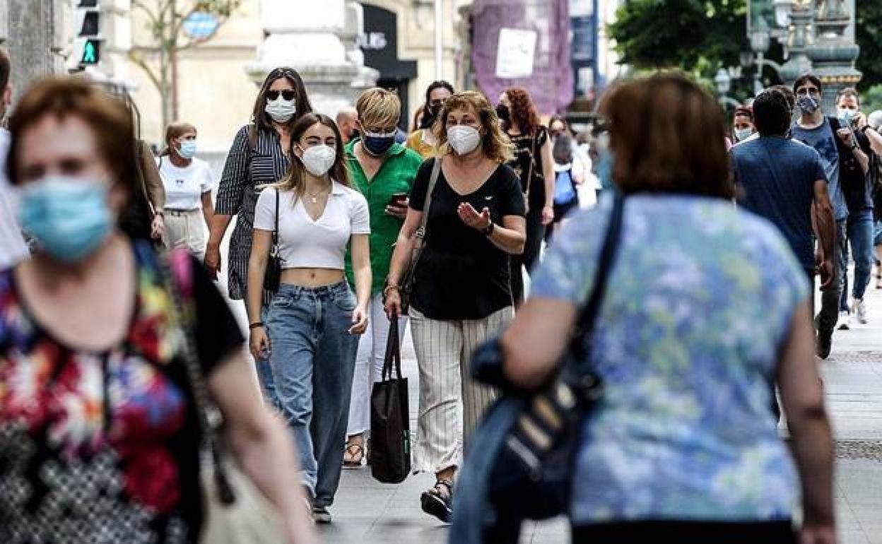 Varias personas pasean por una calle. 