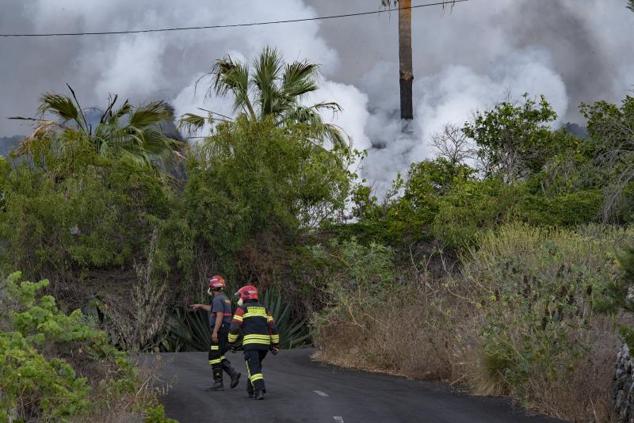 Dos bomberos trabajan en una de las zonas afectadas por la erupción del volcán.