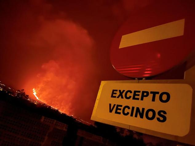 Un letrero y la erupción del volcán en la isla canaria de La Palma.