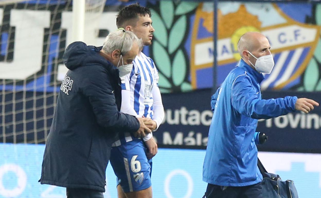 El doctor del Málaga, Pérez Frías, examina el brazo del jugador Ramón tras su lesión.