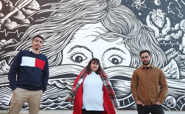 Carlos, Andrea y Pablo, junto al mural situado a la entrada de la Facultad de Ciencias de la Comunicación