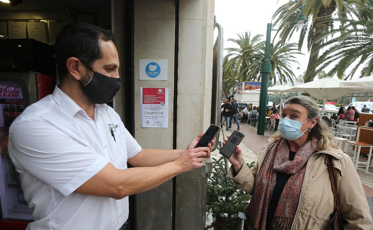 Carlos Muñoz, camarero del Bar Plaza, revisa el certificado de una clienta que quiere pasar al interior. 