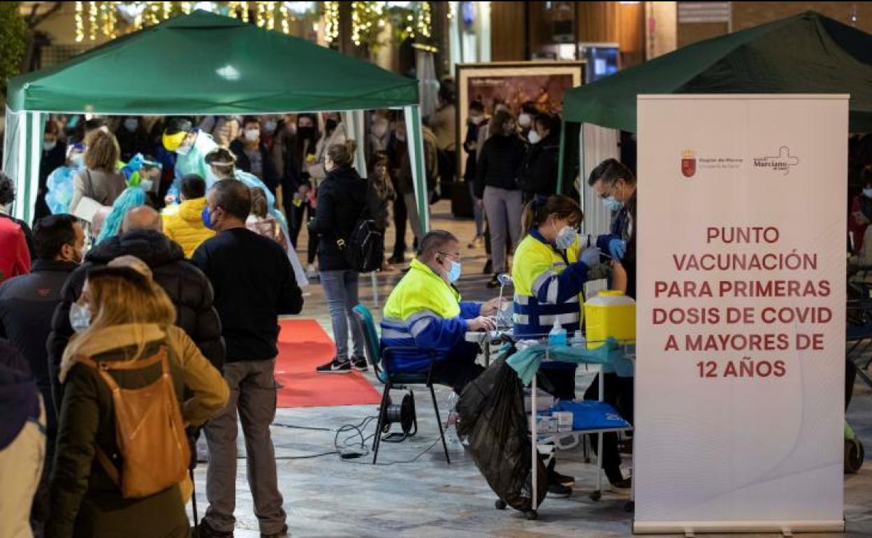 Numerosas personas hacen cola para hacerse un test de antígenos o vacunarse de la primera dosis contra la covid en Murcia.