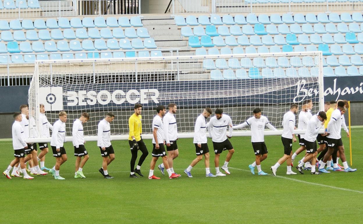 Los jugadores del Málaga trasladan una portería en el entrenamiento de este viernes en La Rosaleda.
