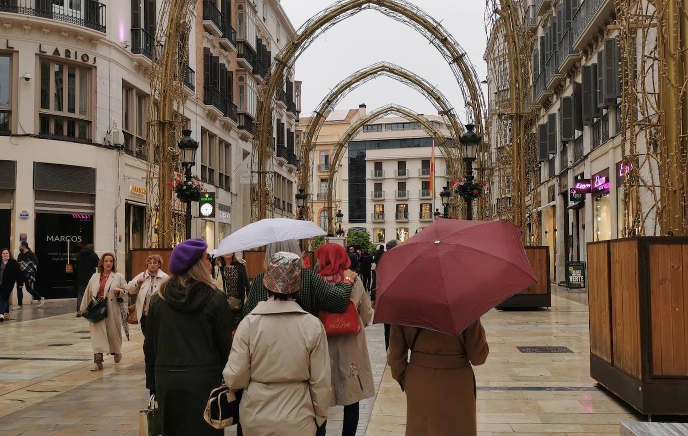 Peatones con paraguas por calle Larios este viernes por la tarde.