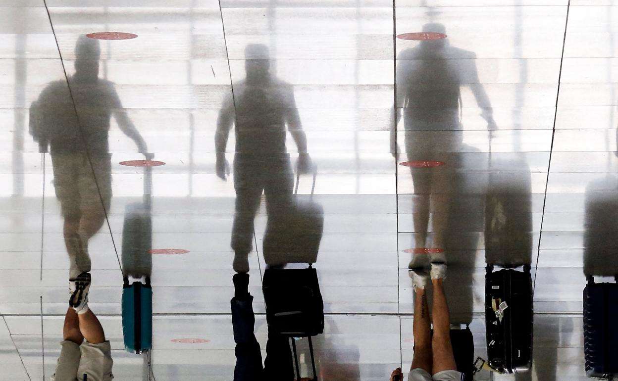 Turistas se desplazan por la terminal de pasajeros del aeropuerto hacia los mostradores de facturación. 