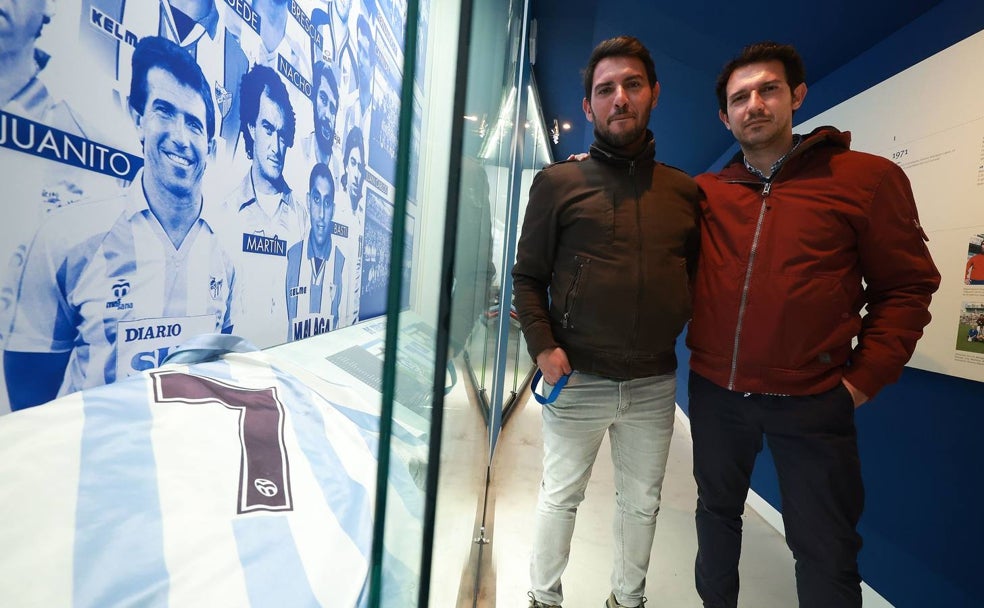 Juan y Roberto Gómez posan en el Museo del Málaga CF junto al retrato y la camiseta de su padre. 