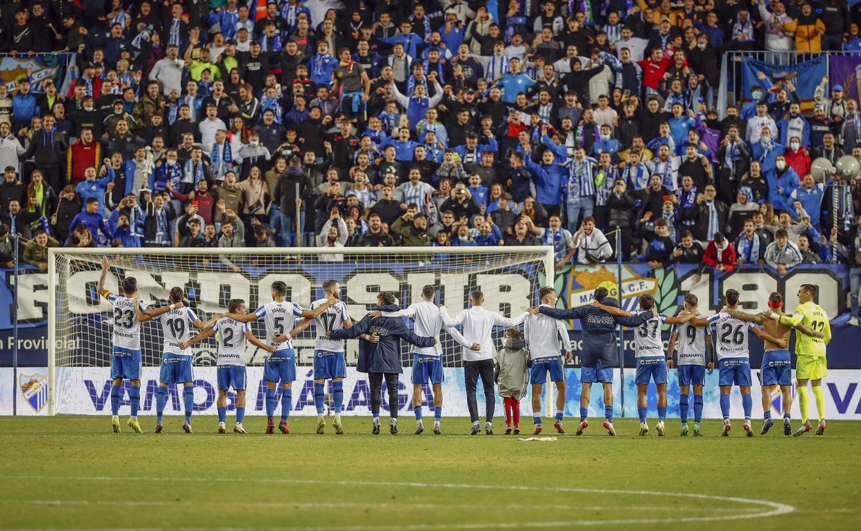 Jugadores del Málaga interactúan con la Grada de Animación en La Rosaleda.