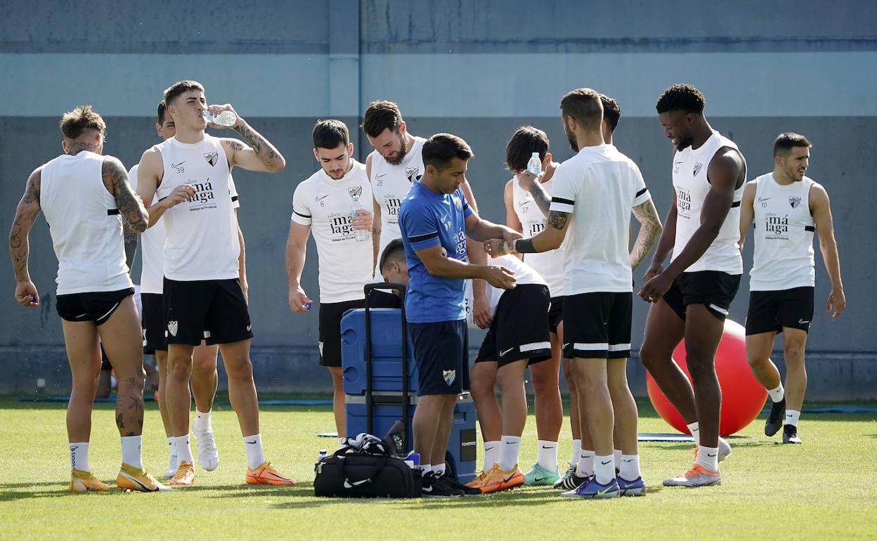 Jugadores del Málaga beben agua durante el entrenamiento de este jueves en el Anexo de La Rosaleda.