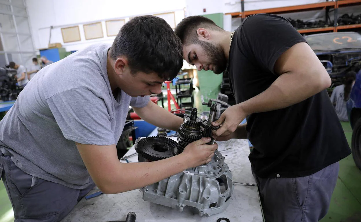 Rafael González Conejo y Antonio Muñoz Paniagua desmontan una caja de cambios manual durante sus prácticas en el instituto. 