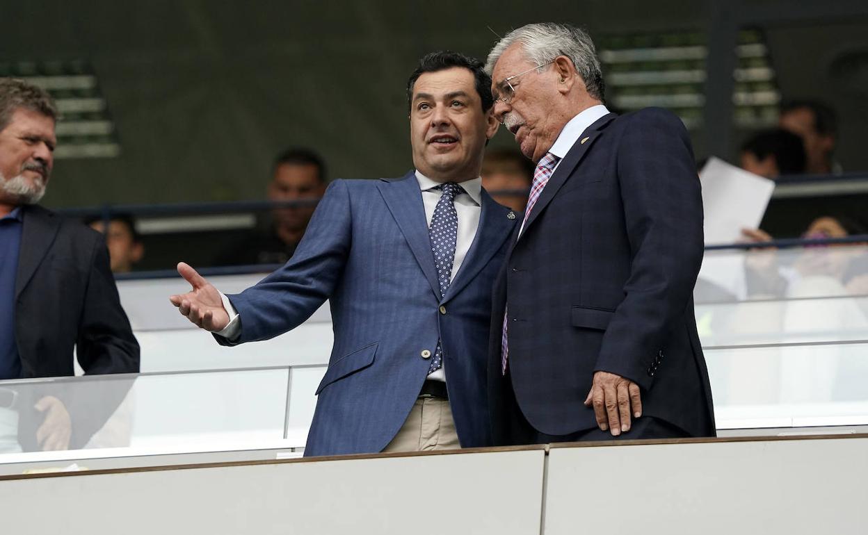 Juanma Moreno dialoga con el consejero Martín Aguilar en el palco de La Rosaleda. 