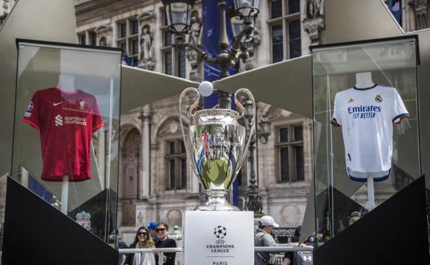 Imagen principal - Arriba, el trofeo de la Champions, flanqueado por las camisetas de los dos equipos finalistas. En las otras dos imágenes, aficionados de Liverpool y Real Madrid disfrutando de la fiesta. 