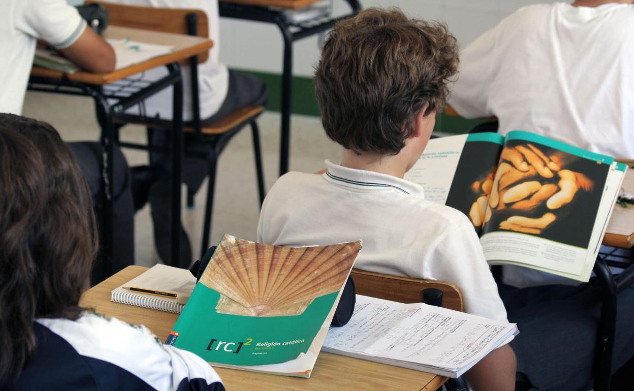 Alumnos, en clase con los libros de religión Católica. 