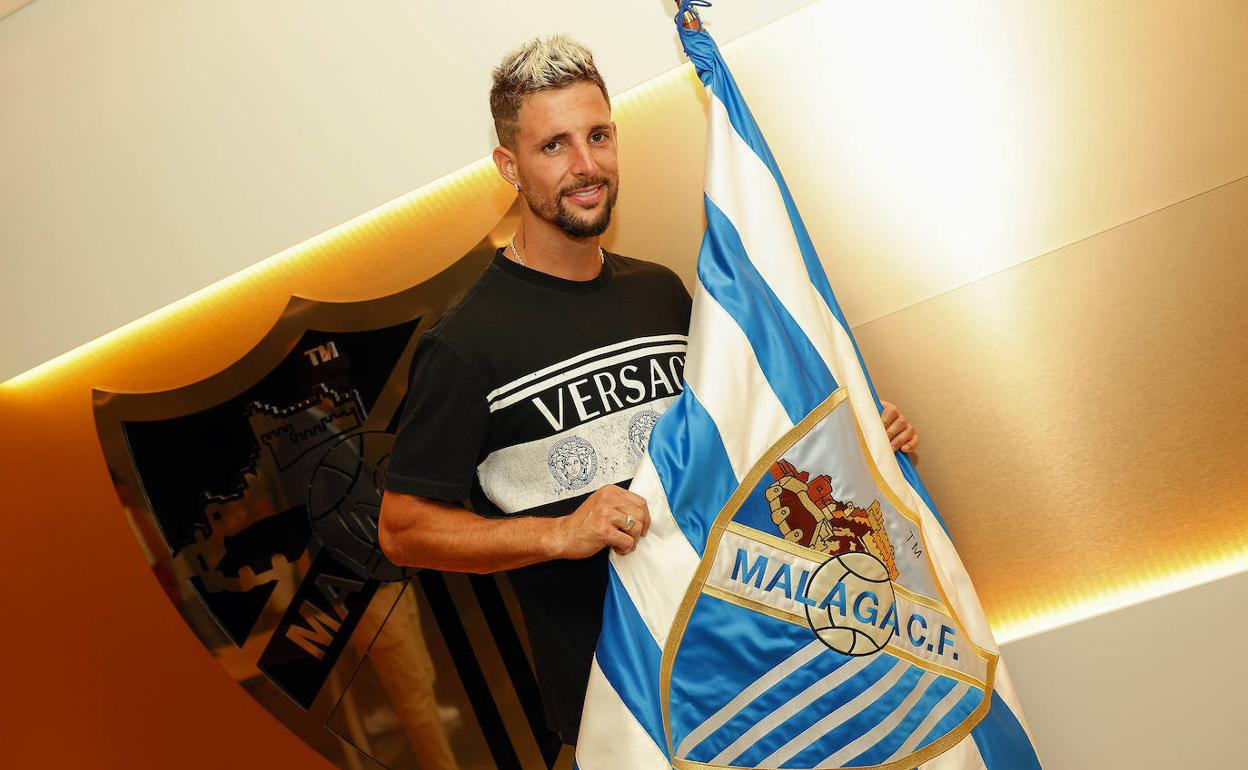 Fran Sol posa con la bandera del Málaga tras firmar. 