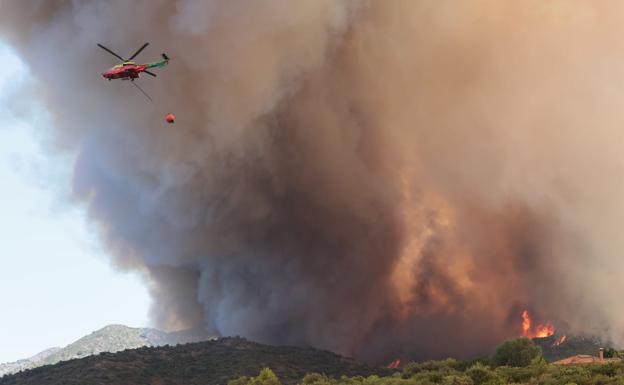 Un helicóptero del dispositivo Infoca realiza una descarga de agua sobre las llamas, que alcanzaron los 20 metros de altura. 